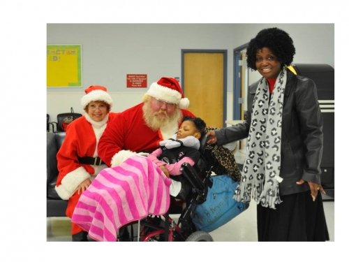 Santa and Mrs. Claus standing with a Special Populations Participant and family