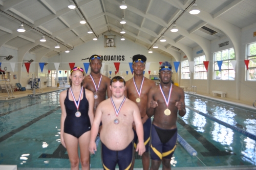 Group of teens standing in front of a pool wearing honorary medals